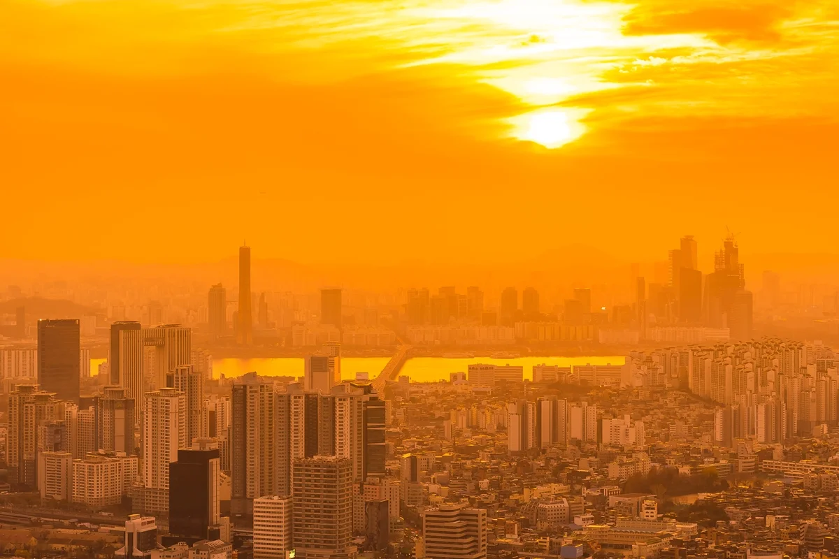 Imagem colorida mostra cidade com sol no fundo - Metrópoles