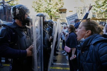 A woman shouts at riot police holding shields during a protest in Tirana