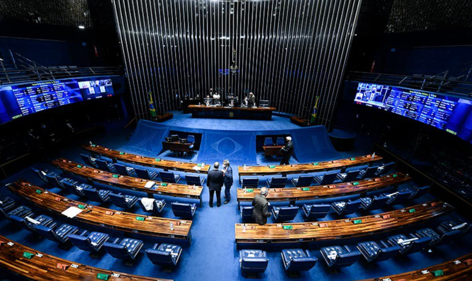 Foto do Plenário do senado, com tapete azul e cadeiras em madeira