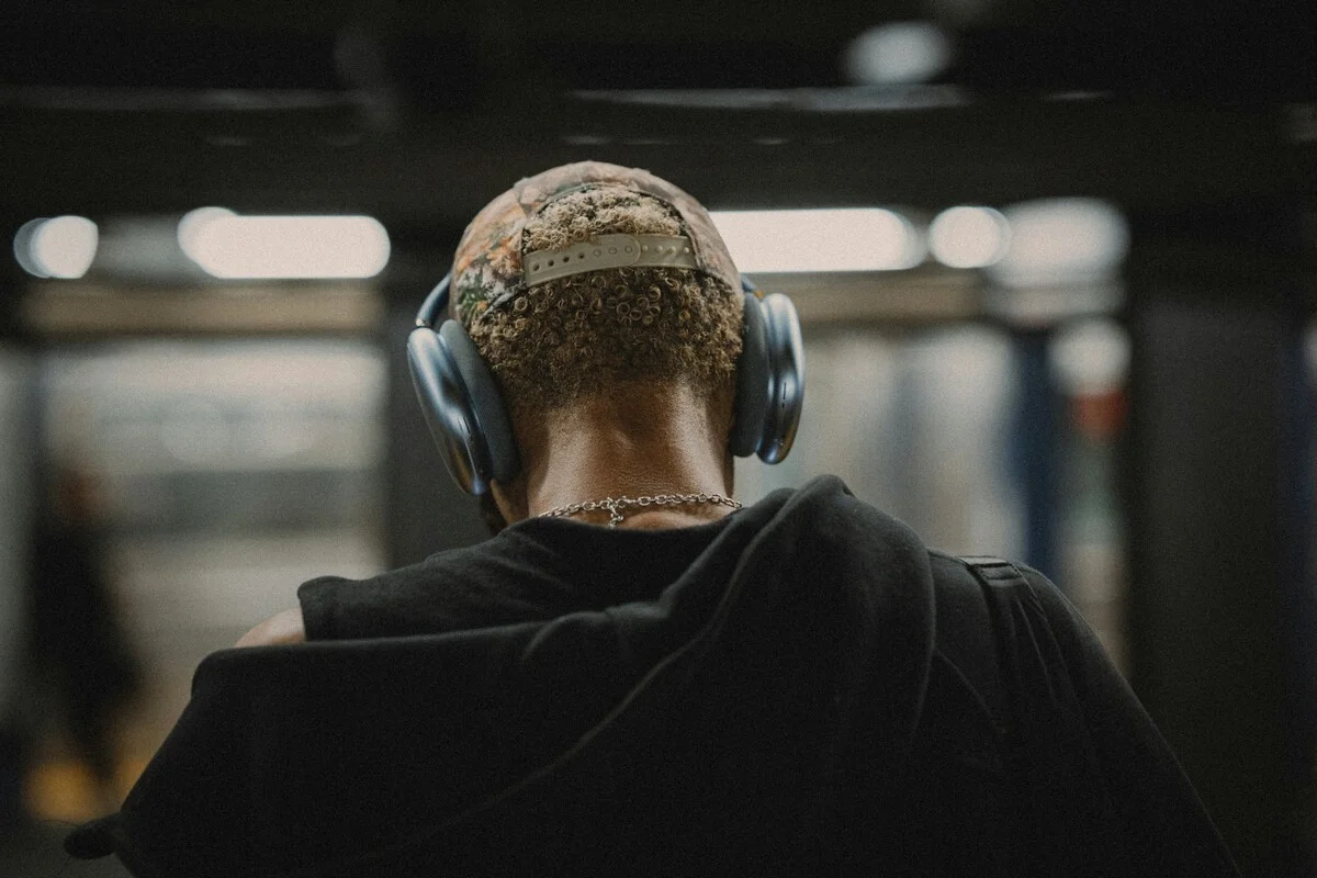 Pessoa na estação de metrô concentrada ouvindo música