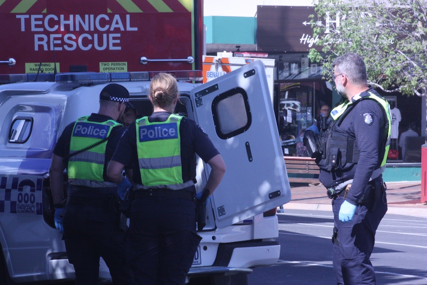 Police officers surround a police van, with Brendan Nugent sitting inside.