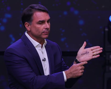 Flávio Bolsonaro gestures while showing writing on his palm during a televised debate