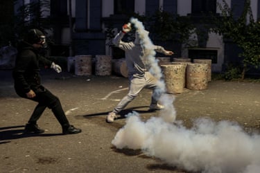 A protester throws a smoking tear gas canister back towards police during a Tirana protest