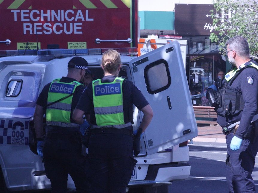 Police officers surround a police van, with Brendan Nugent sitting inside.